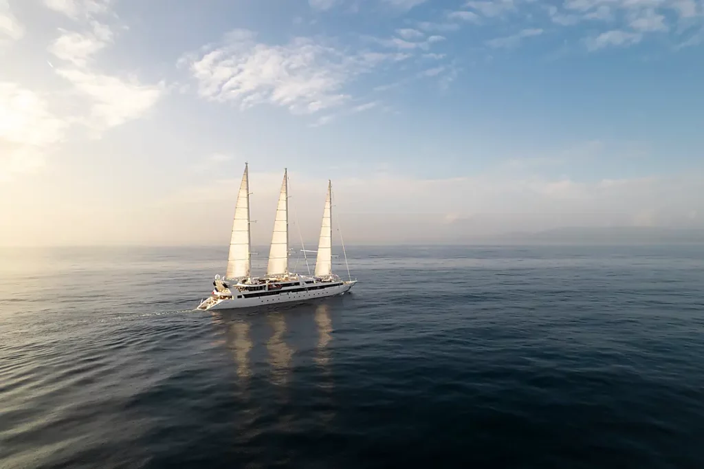 Voilier Le Ponant en croisière dans les Caraïbes sur une mer calme au coucher du soleil