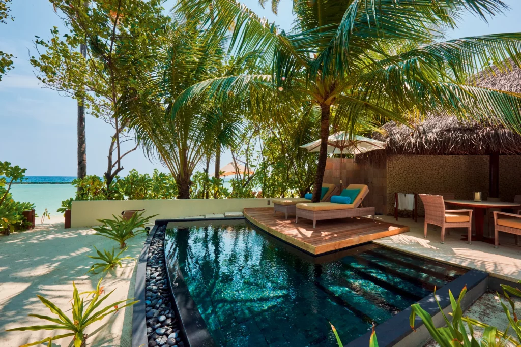 Beach Villa du Constance Halaveli Maldives avec piscine privée, plage de sable blanc et palmiers face au lagon turquoise. 