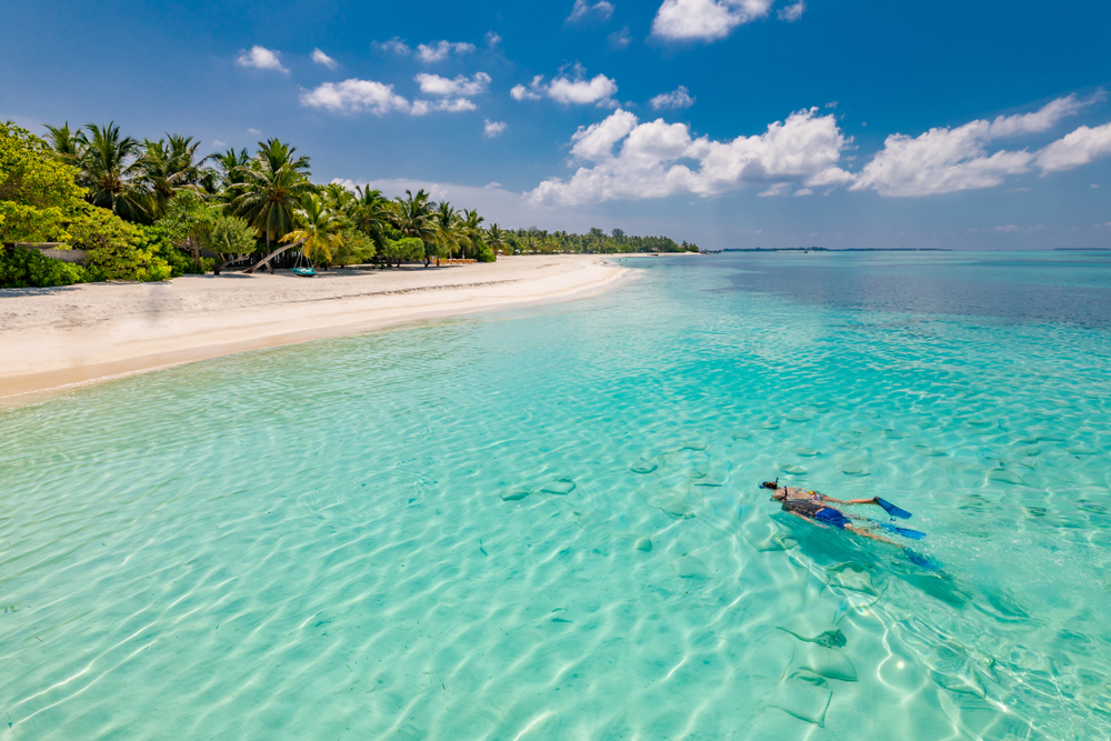 Snorkeling au Constance Halaveli Maldives, nageur au-dessus des coraux et poissons tropicaux dans un lagon turquoise.