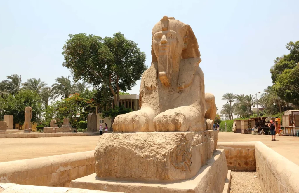 Colosse de Ramsès II à Memphis, vestige emblématique de l’Égypte antique entouré de palmiers et de sites historiques.
