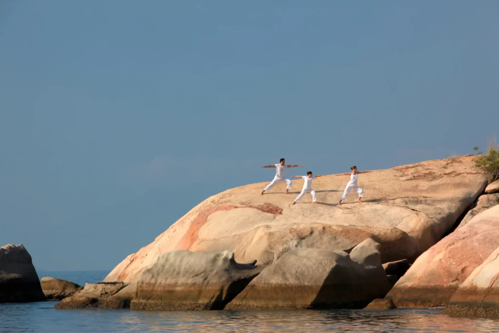 Séance de yoga sur les rochers face à la mer dans une baie au Vietnam