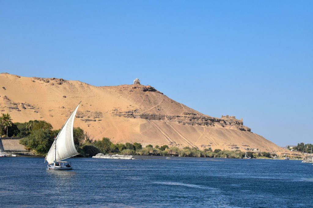 Felouque traditionnelle naviguant sur le Nil dans les paysages désertiques d’Assouan